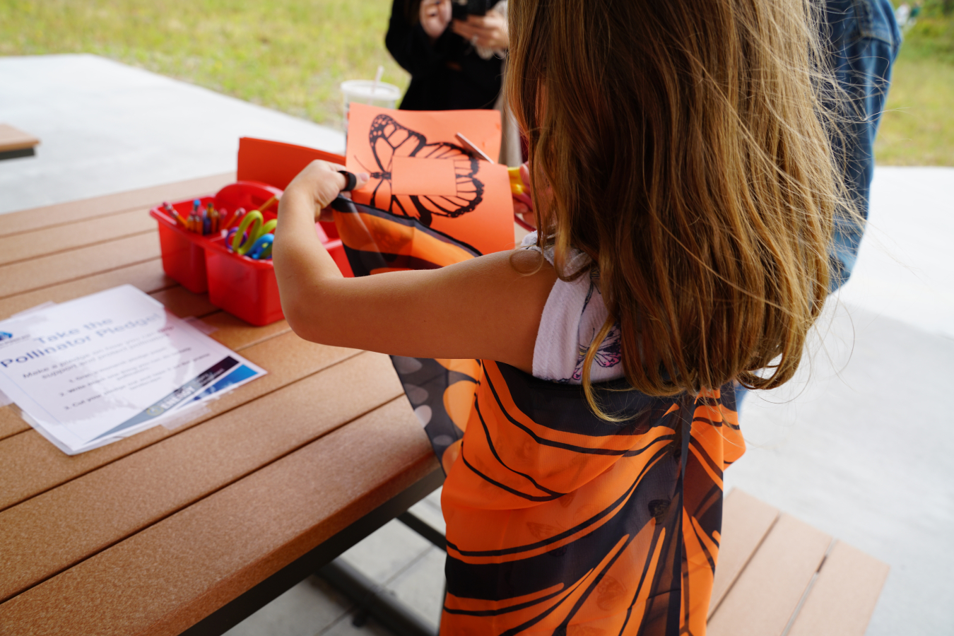 A young visitor cuts out a butterfly pattern at the Kid’s Craft Pavilion station.
