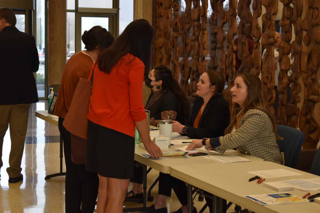Three employees at table welcome attendees