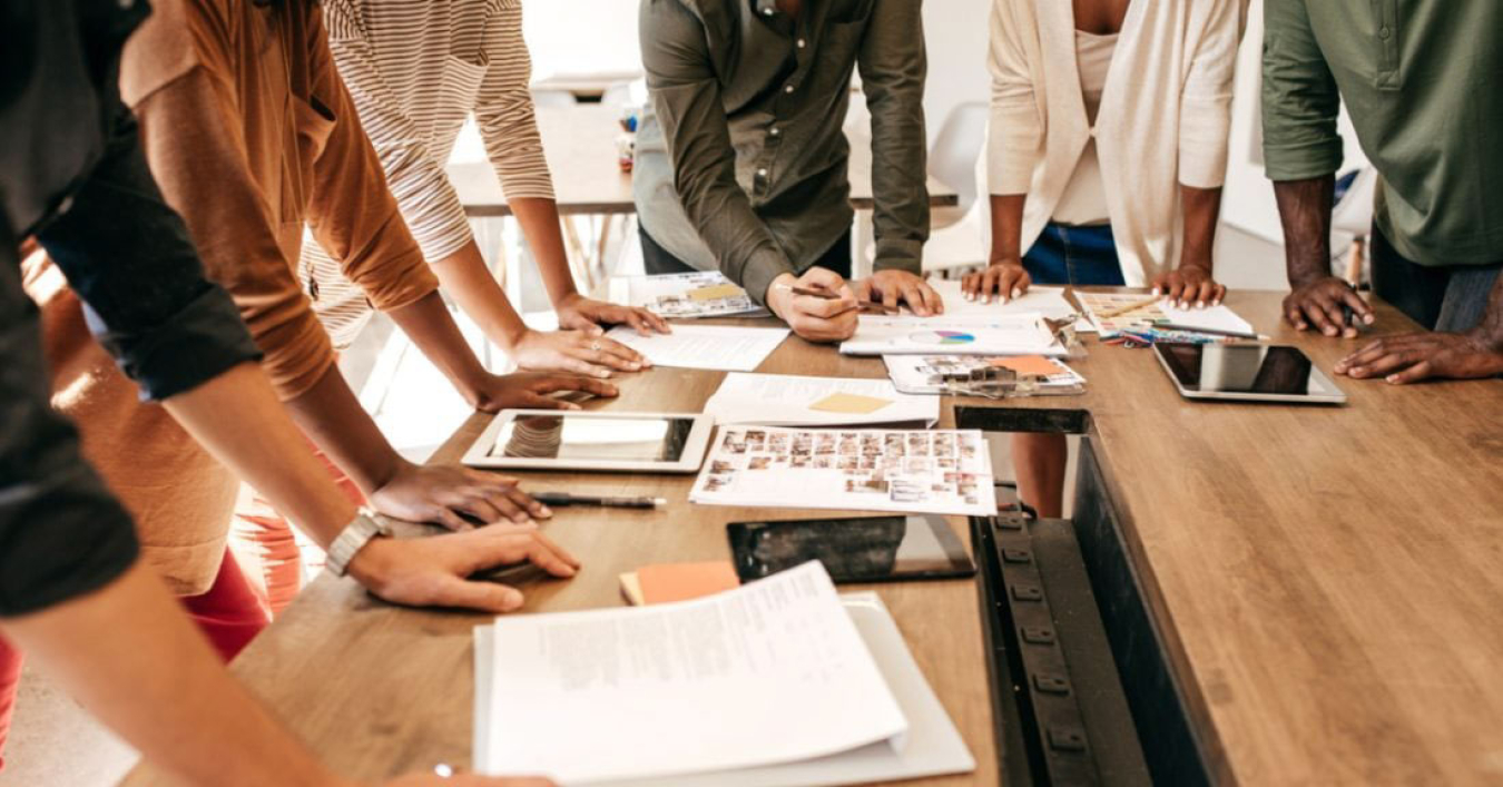 Team members' hands resting on desk while reviewing project notes