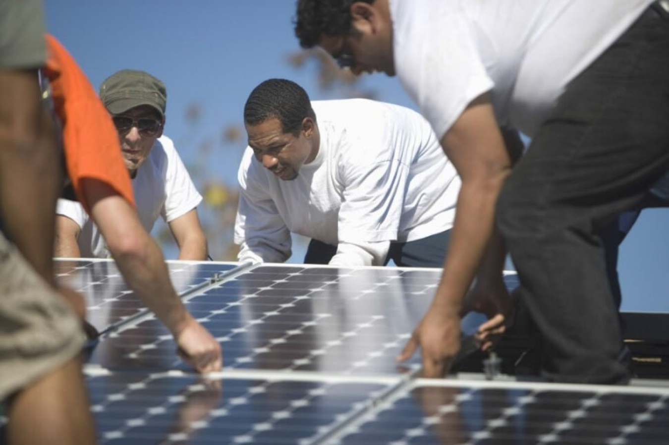 Several men work together to install a solar panel