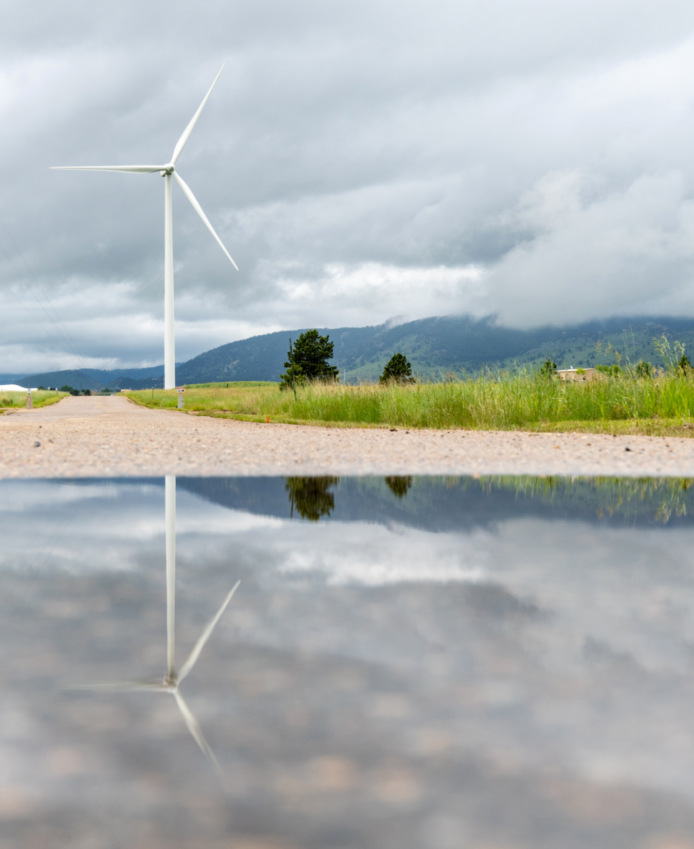 A distant wind turbine creates a reflection in a pond.