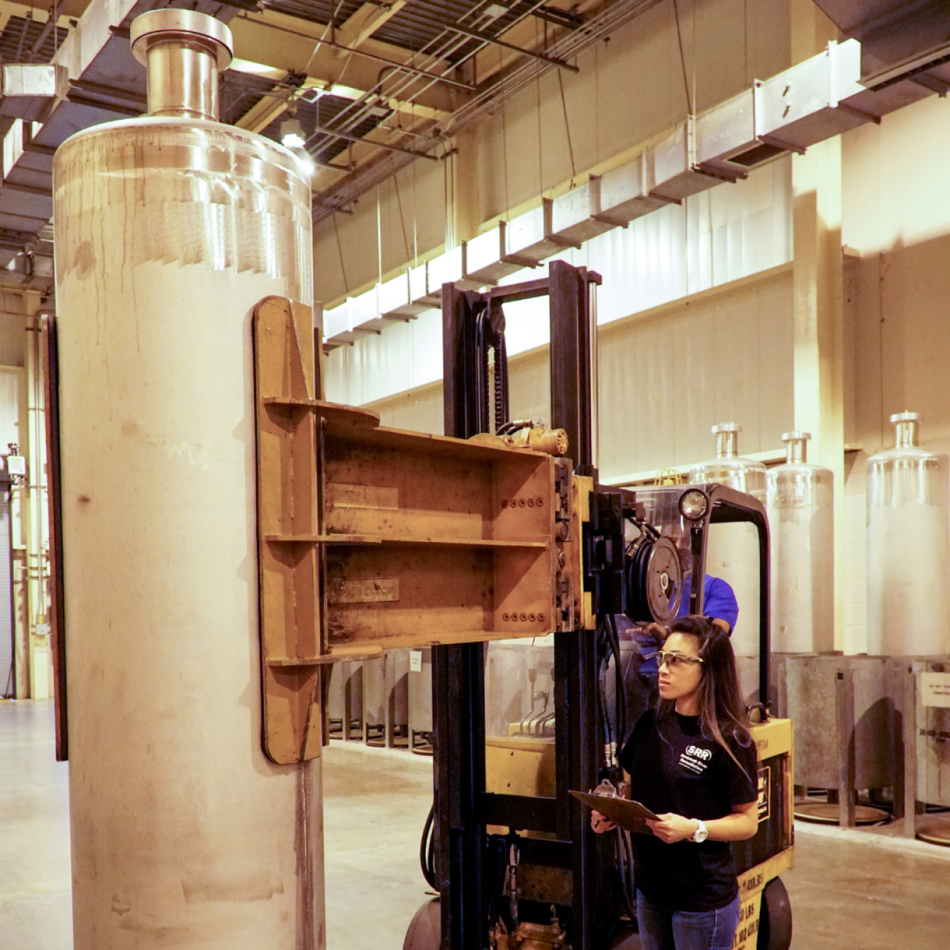 Female employee observes stringent safety standards while moving a 10-foot-tall, stainless steel canister.