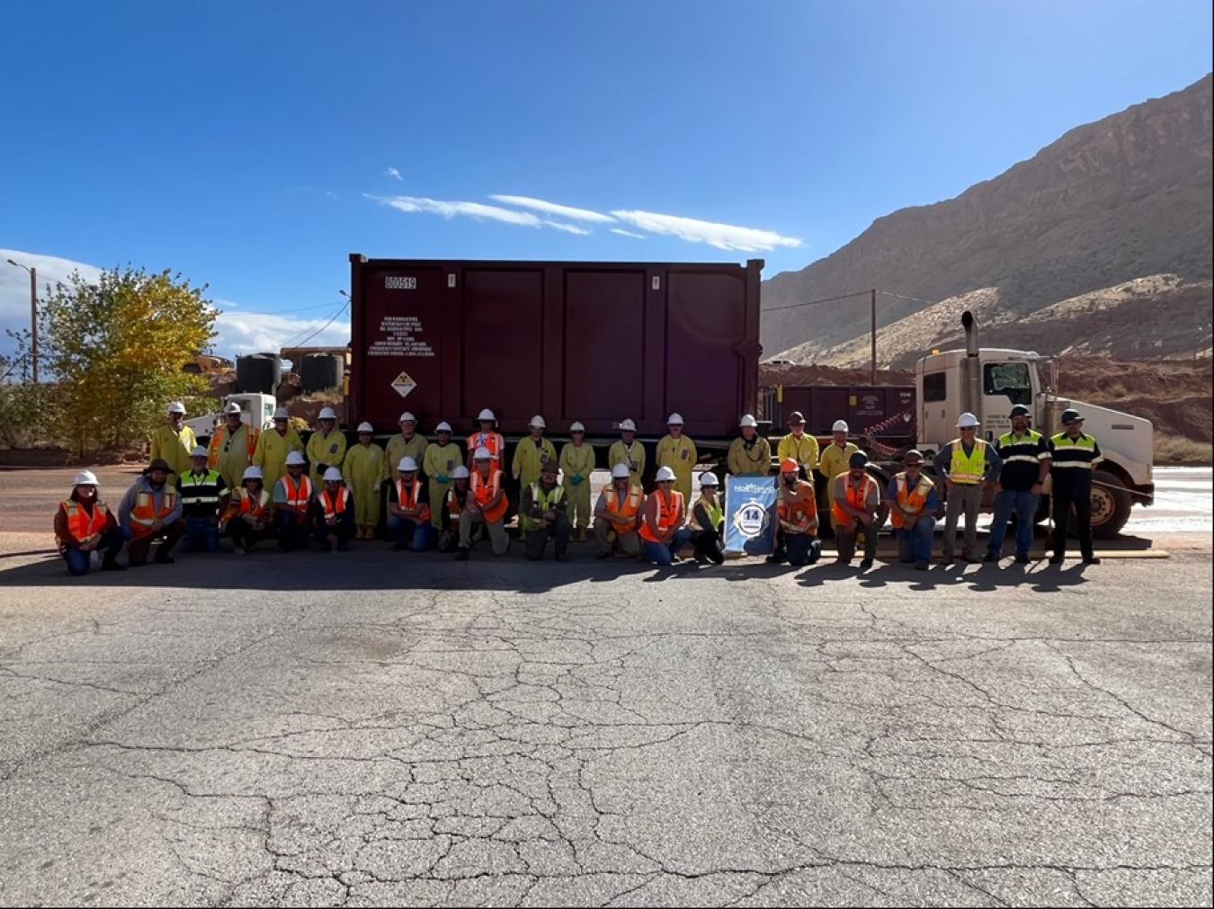 Workers in hardhats posed with truck hauling mill tailings