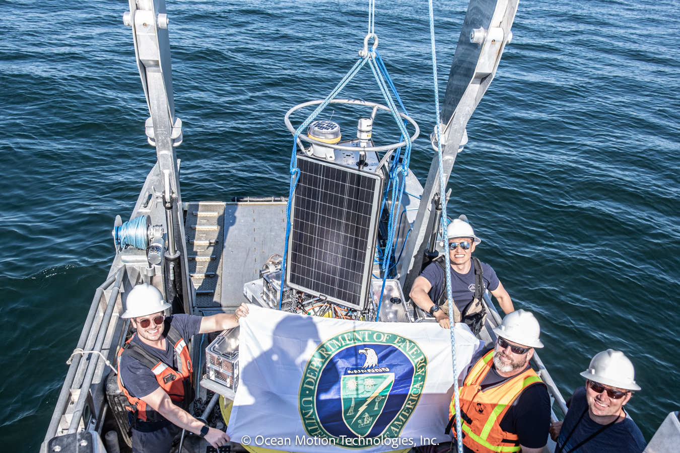 Four people with a Department of Energy flag on a small surface at sea.