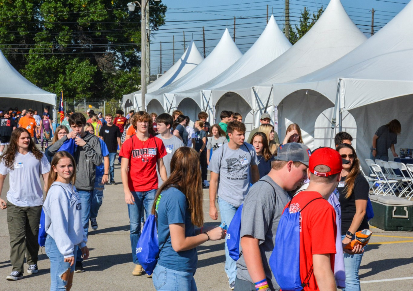 A walkway between big white tents filled with people