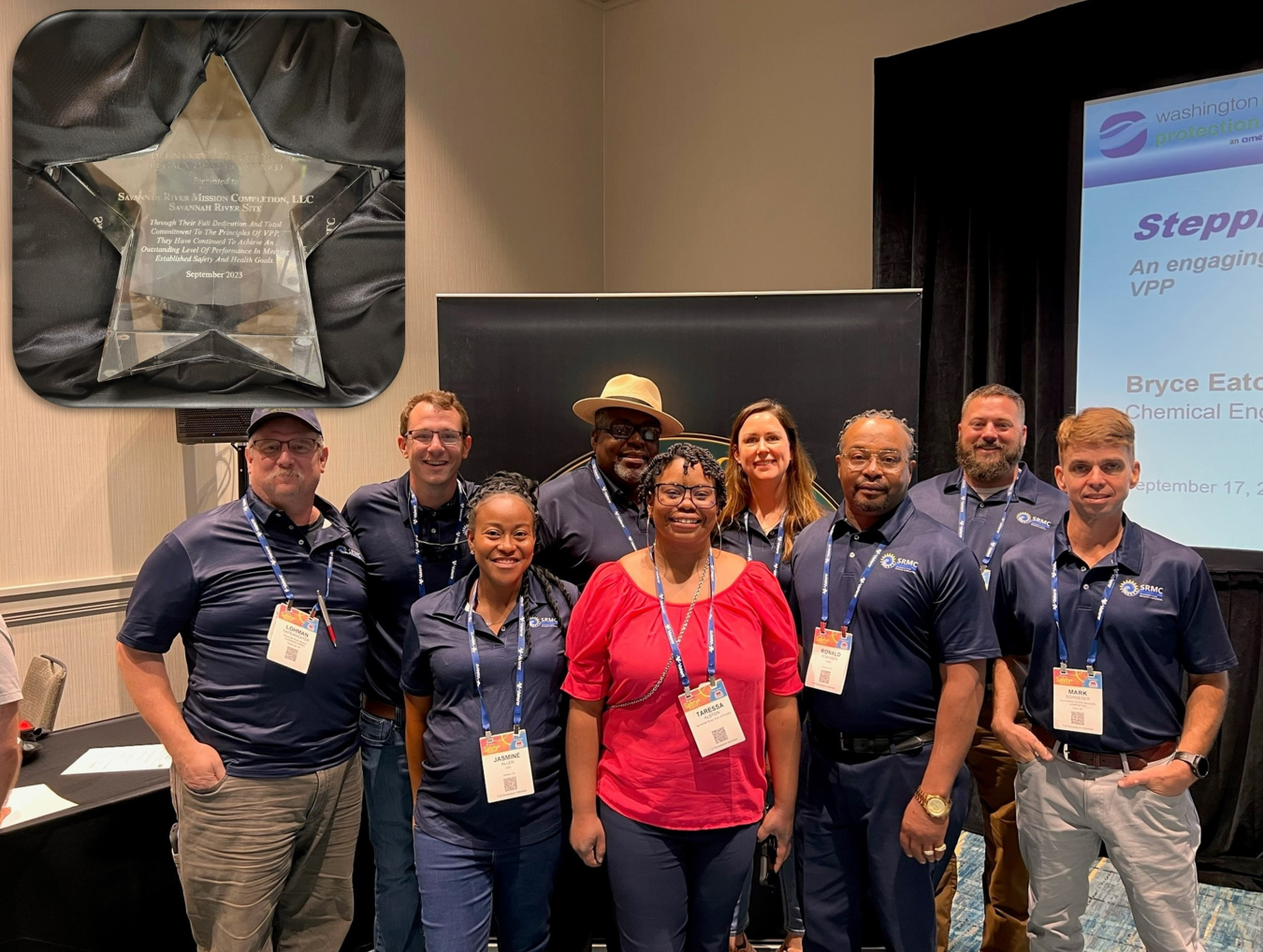 A group of employees pose in front of the award they received