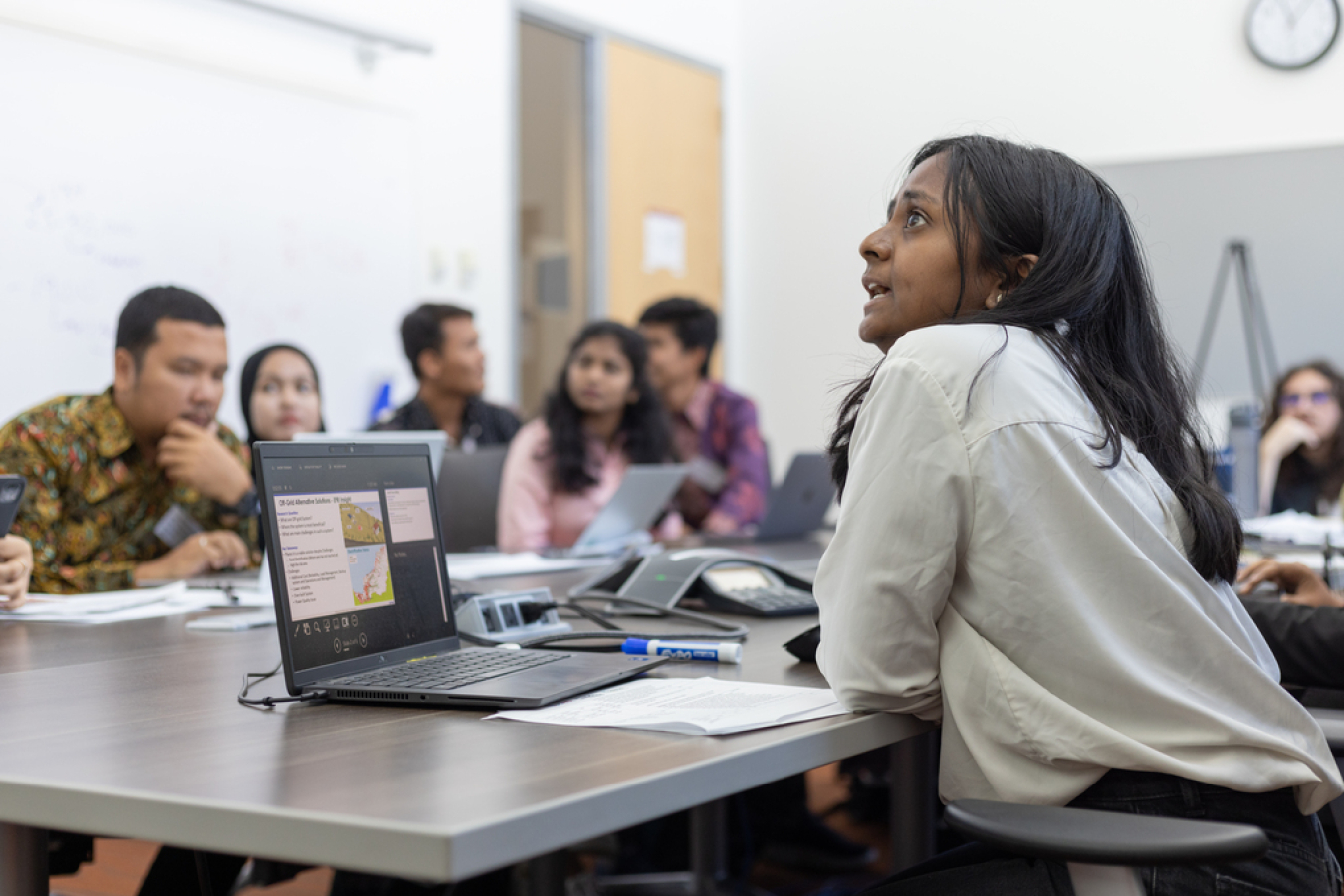 An intern sitting at a table presenting to other interns.