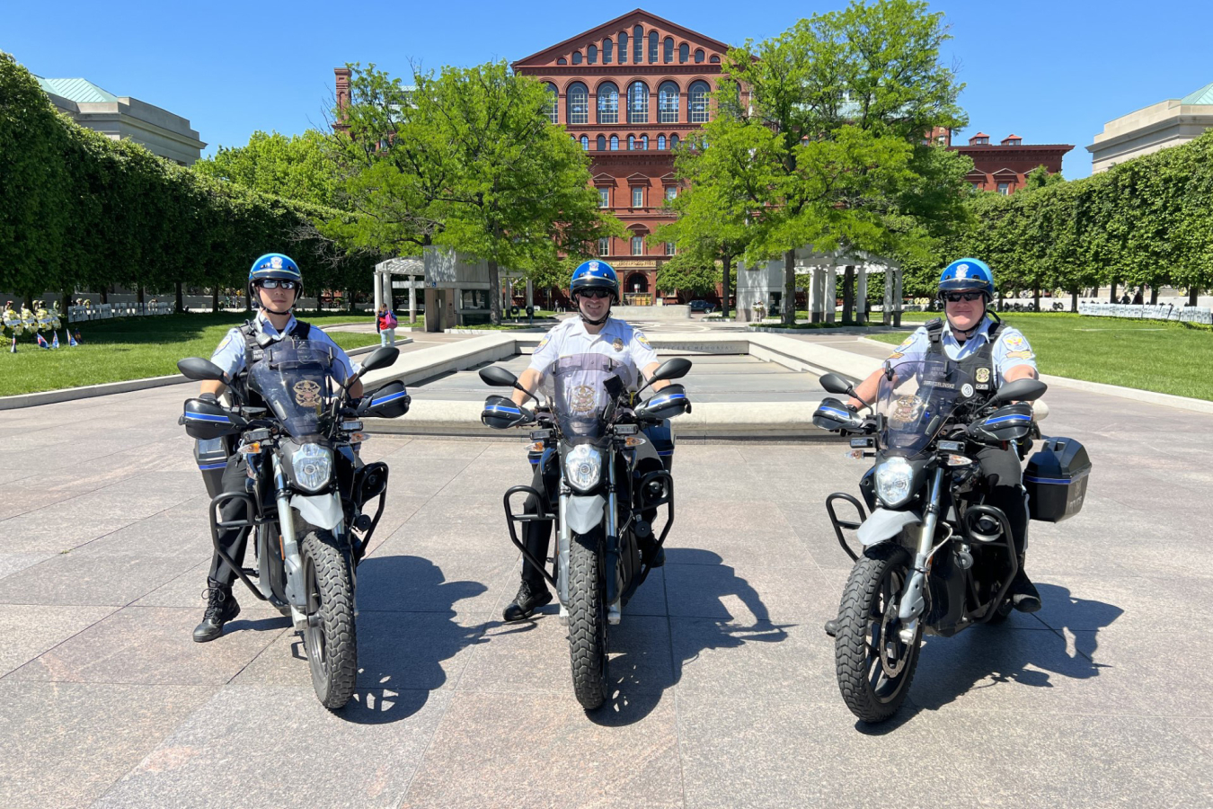 Three police officers sit on electric motorcycles on the National Mall in Washington, D.C.