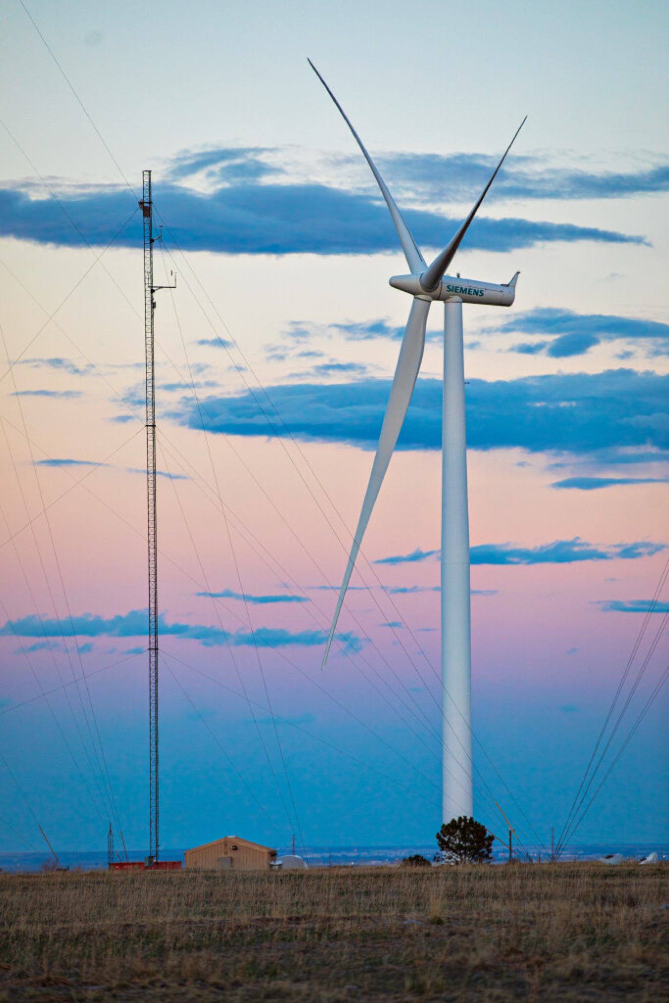 The sun sets behind a wind turbine. 