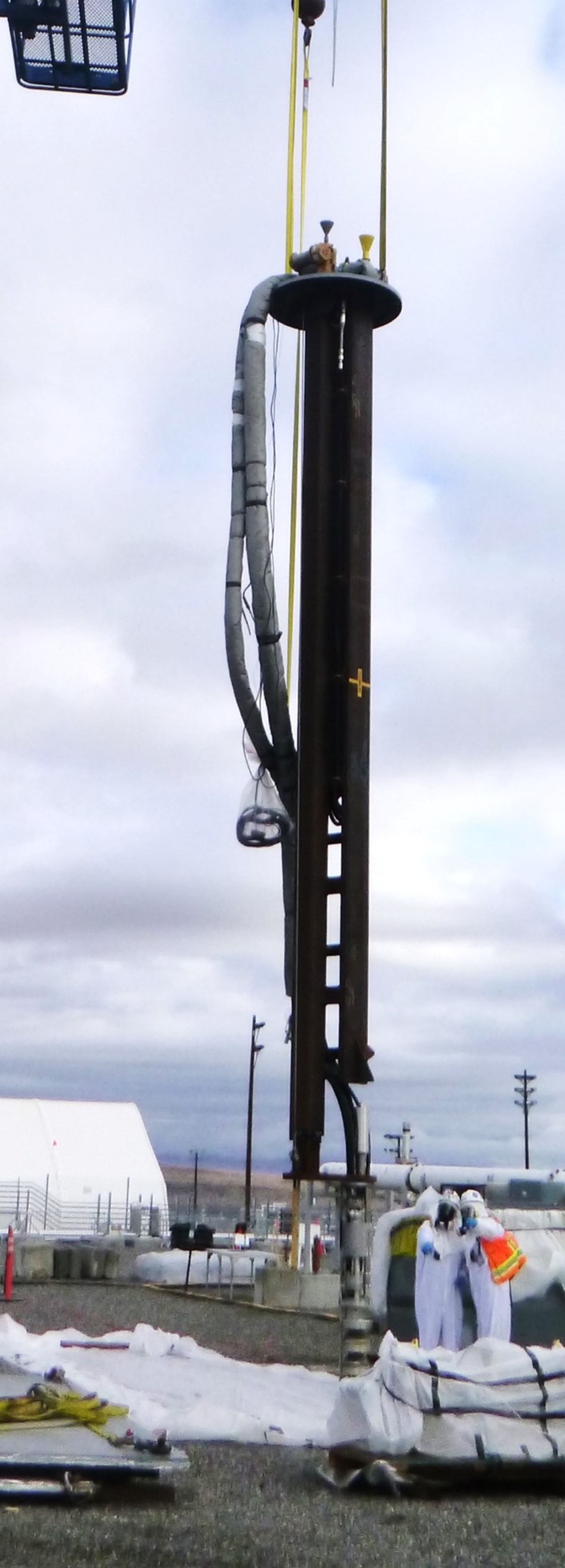 A large black crane lowering a pump