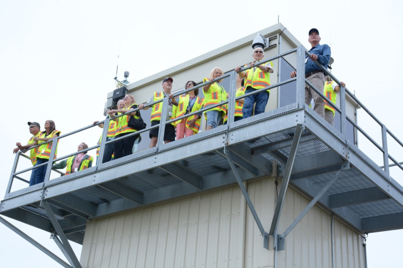 People in neon yellow safety jackets stand on top of an overlook area