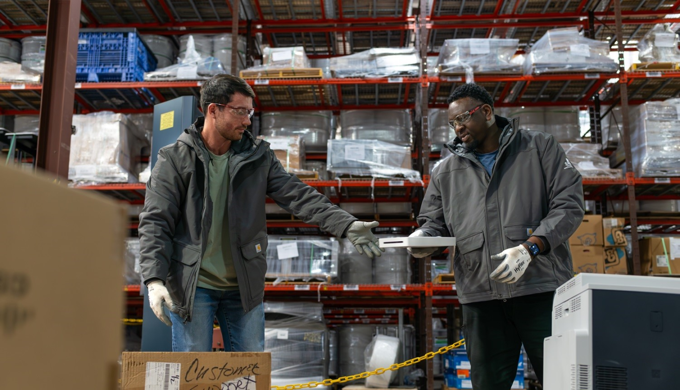 Two workers pass materials in a white box to each other