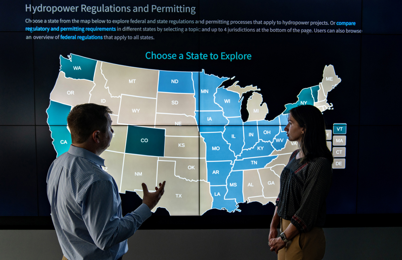 Researchers stand in front of a video screen with the RAPID Toolkit displayed on it