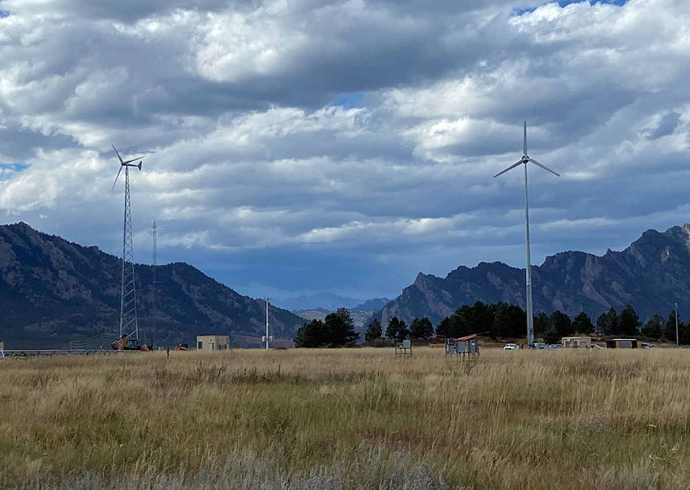 Multiple wind turbines in a filed outlined by mountains. 