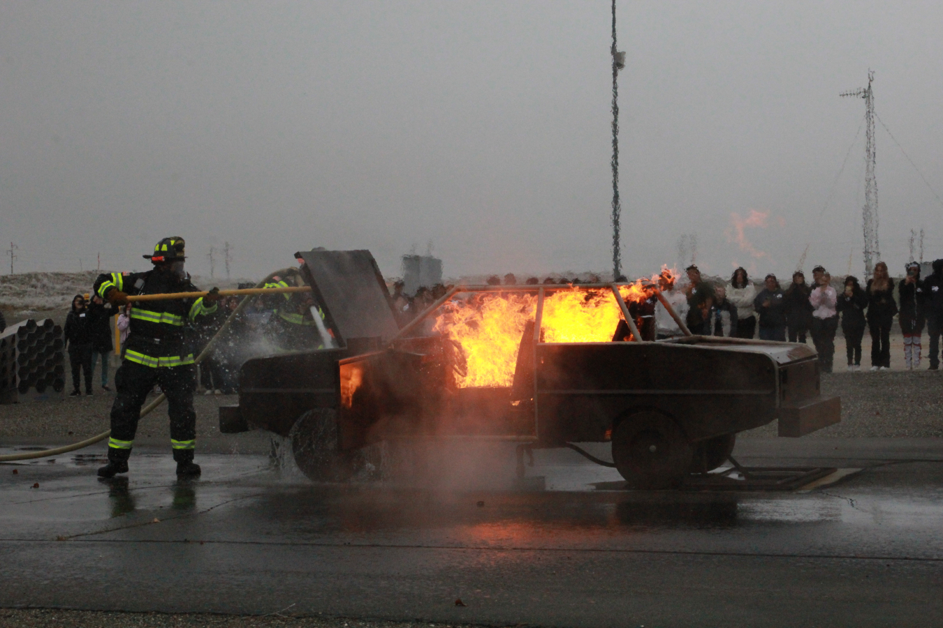 A firefighter puts out a car on fire