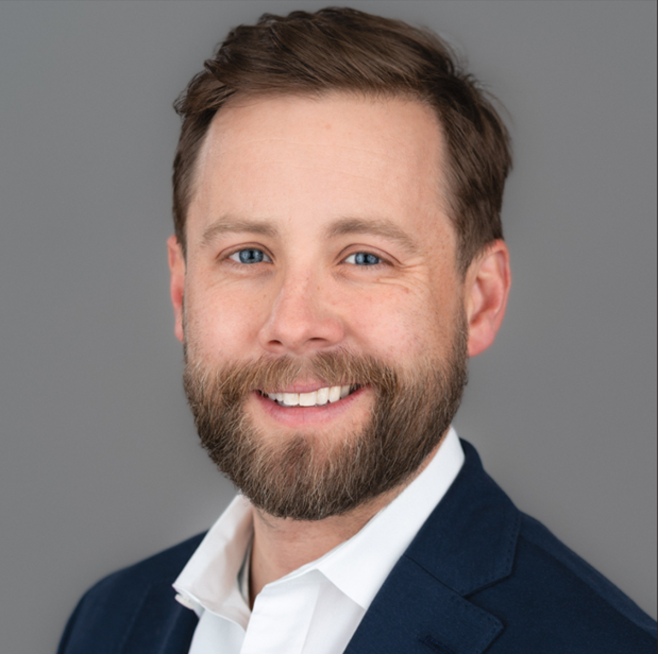 Portrait of man with beard wearing suit jacket.