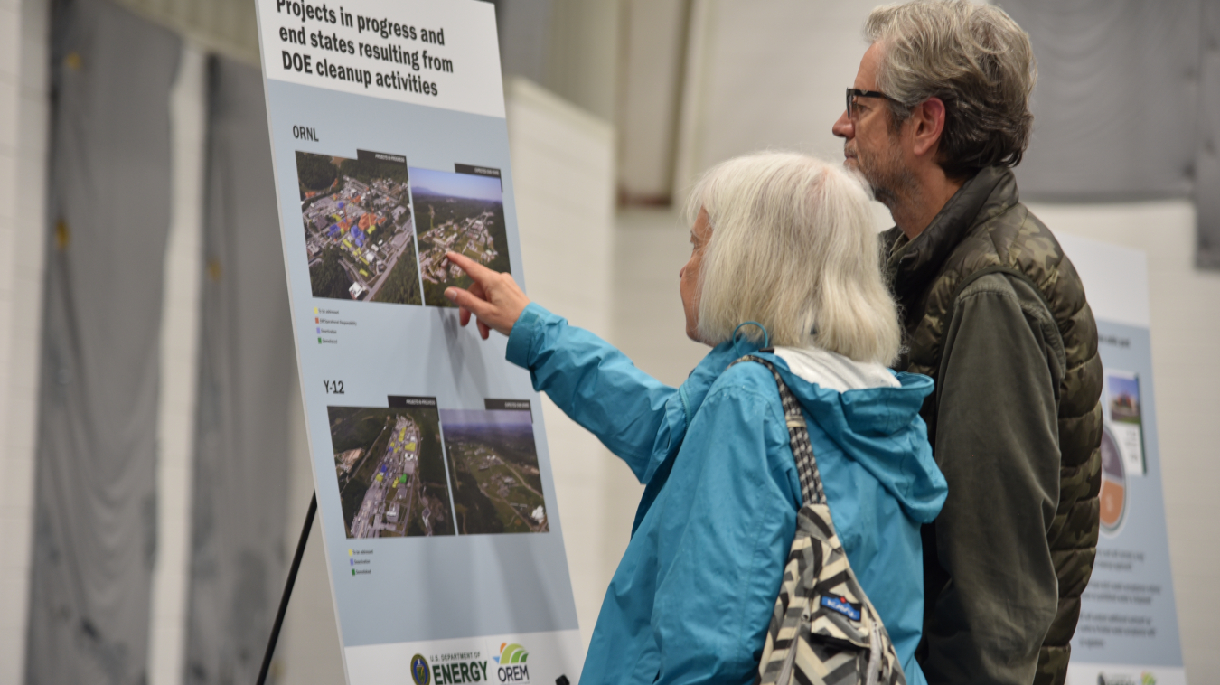 Two people looking at a poster of information about cleanup projects.