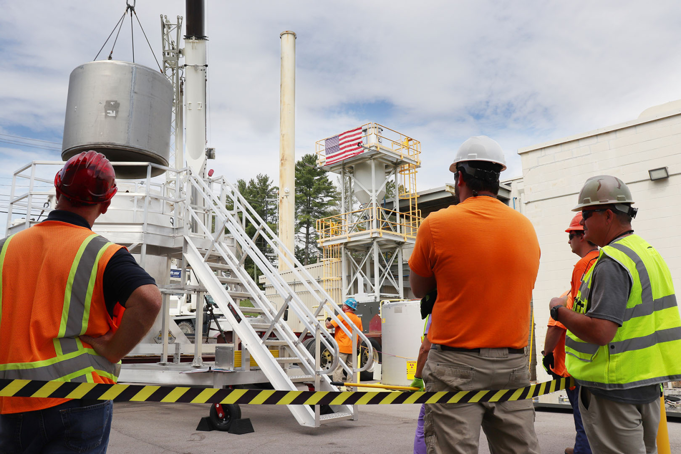 Employees load material into a large white machine