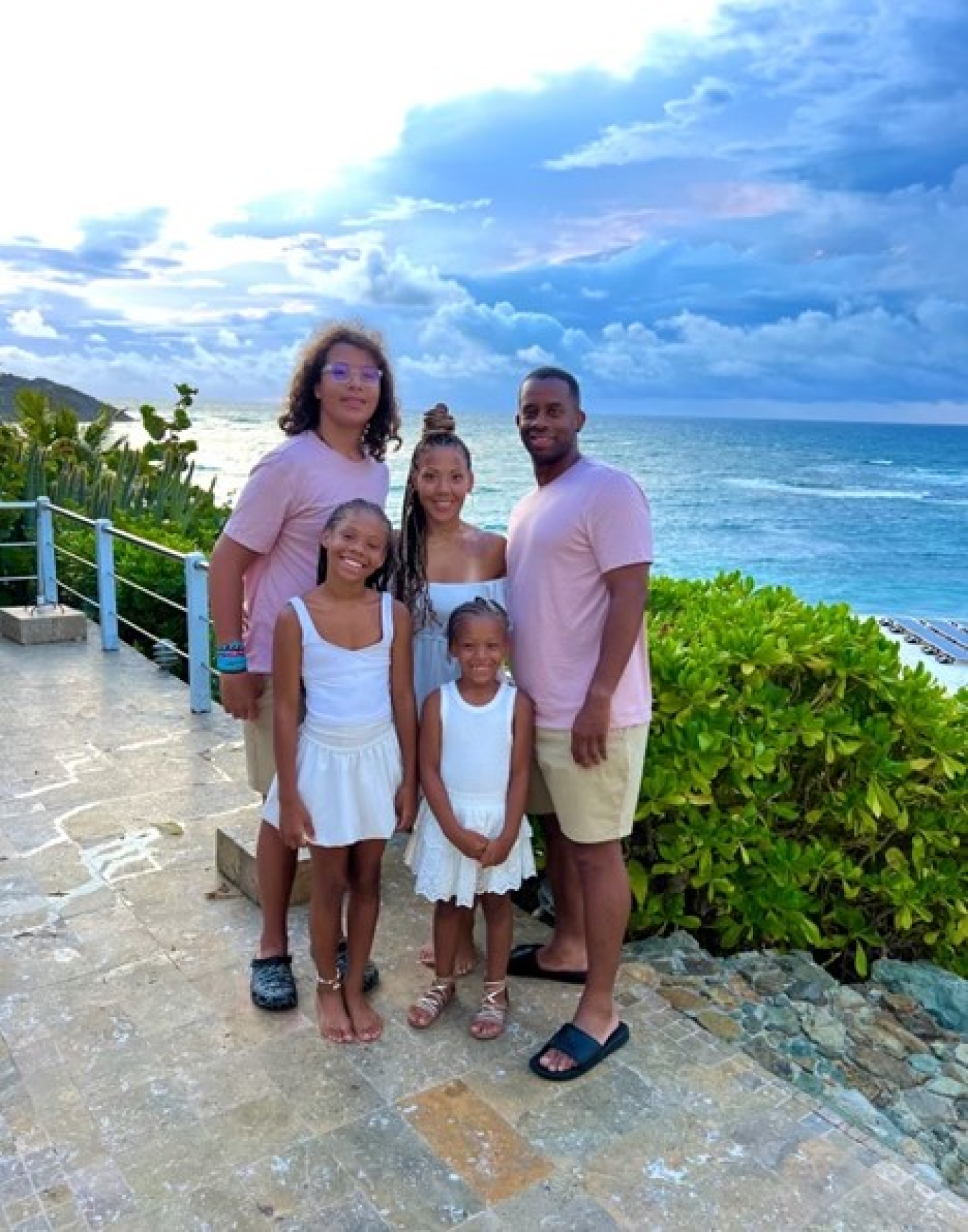 Jen posing with her husband and three kids in front of the ocean