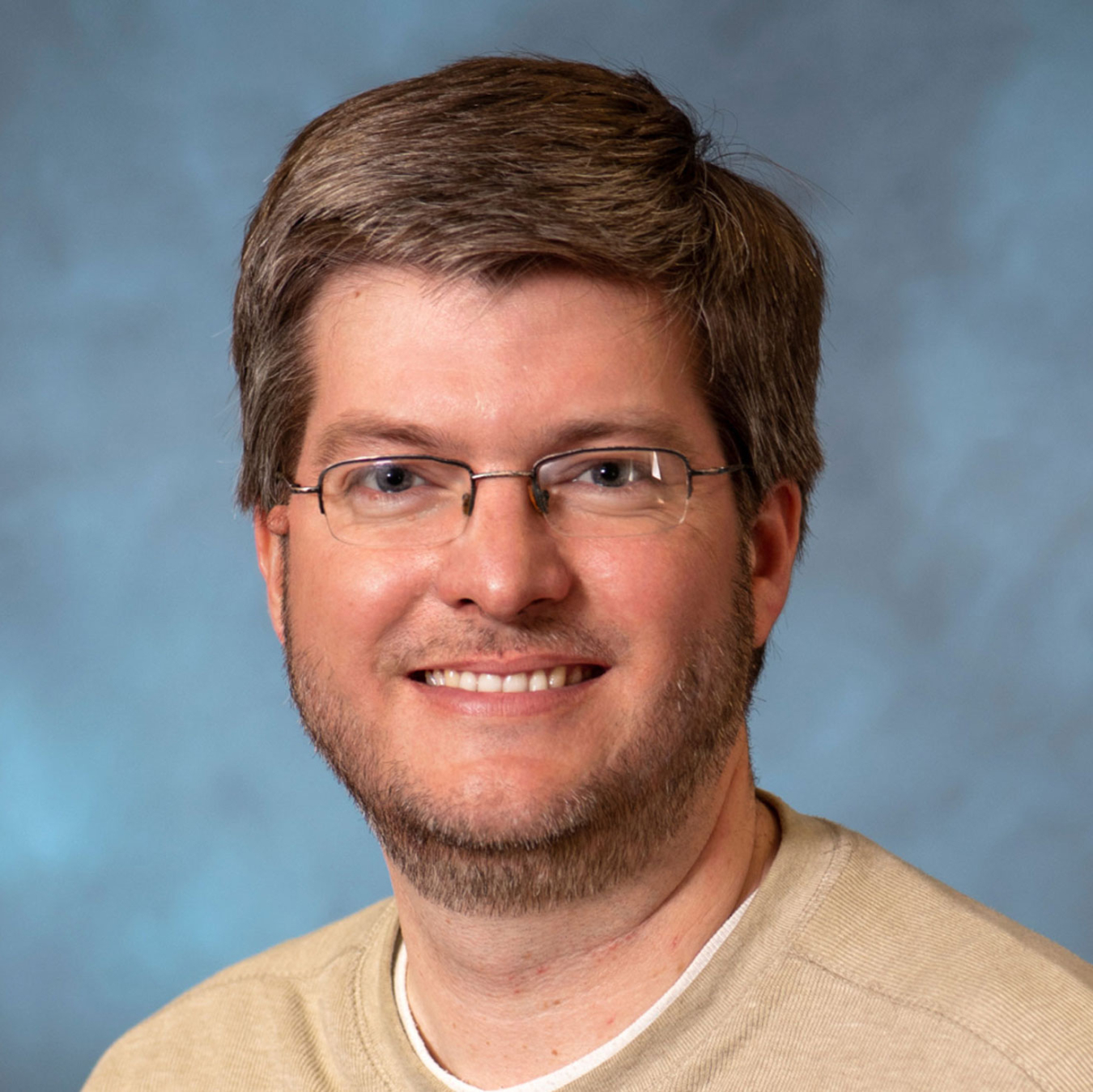 Brandon Wood, smiling, wearing glasses and a shirt.
