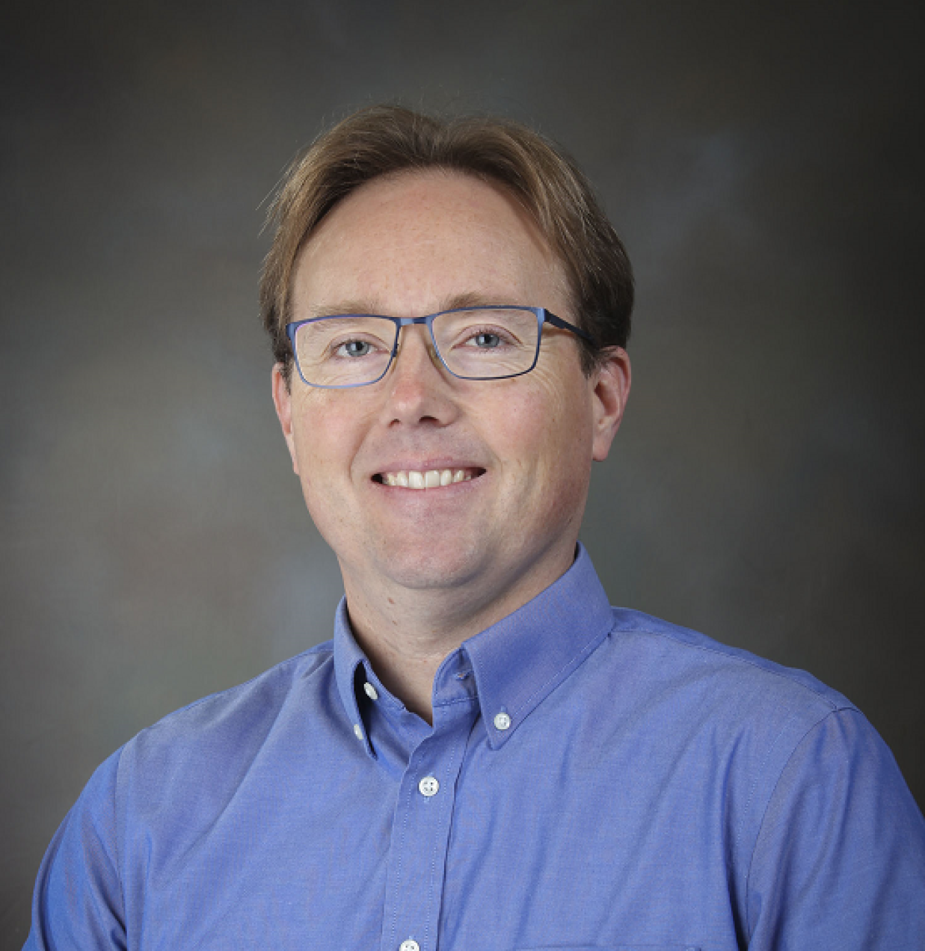 Sean Bishop, smiling, wearing glasses and a collared shirt.