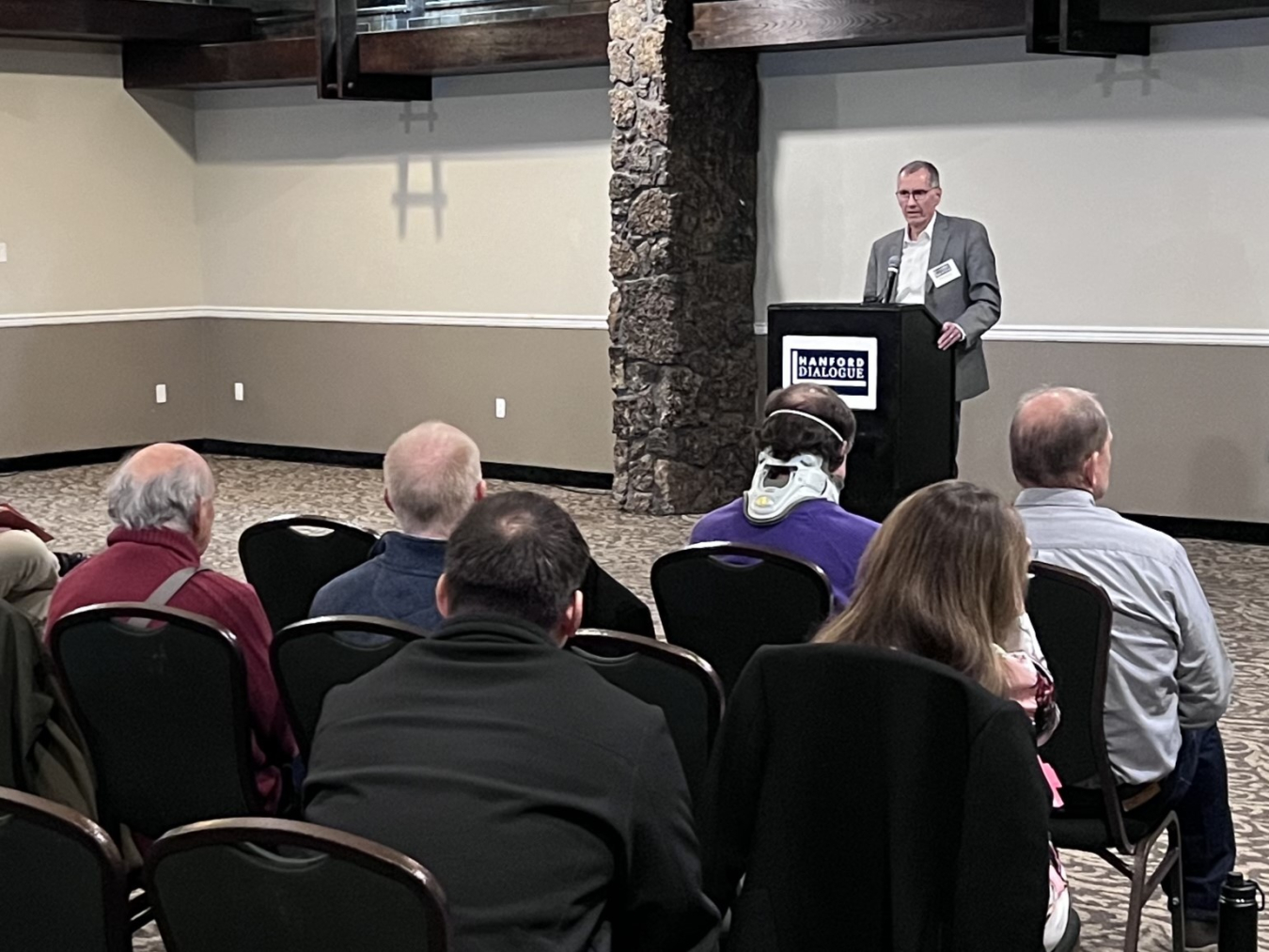 A man stands at a podium at the front of a room while the audience looks at him