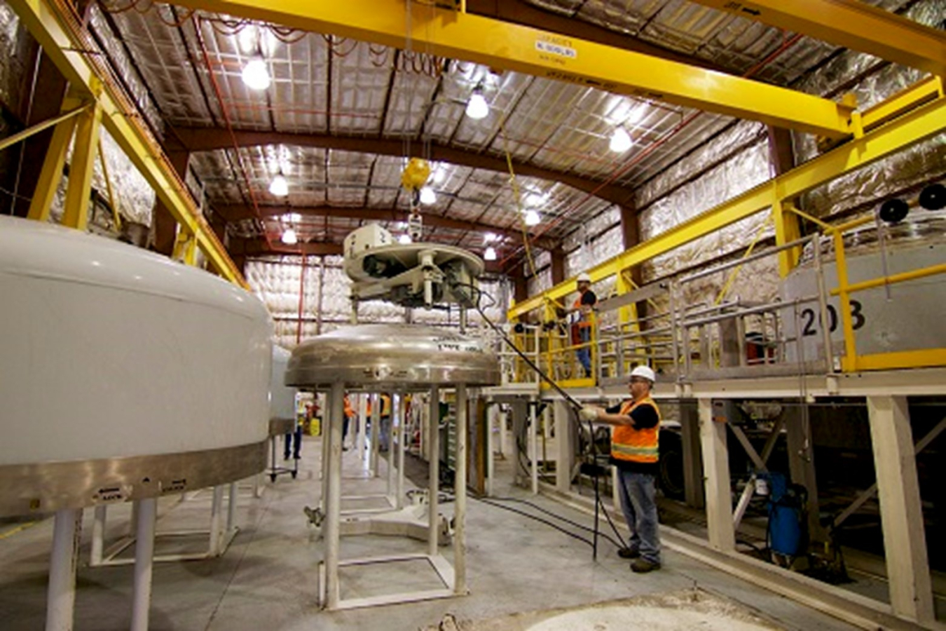 Worker in a large factory building uses a machine to prepare waste containers