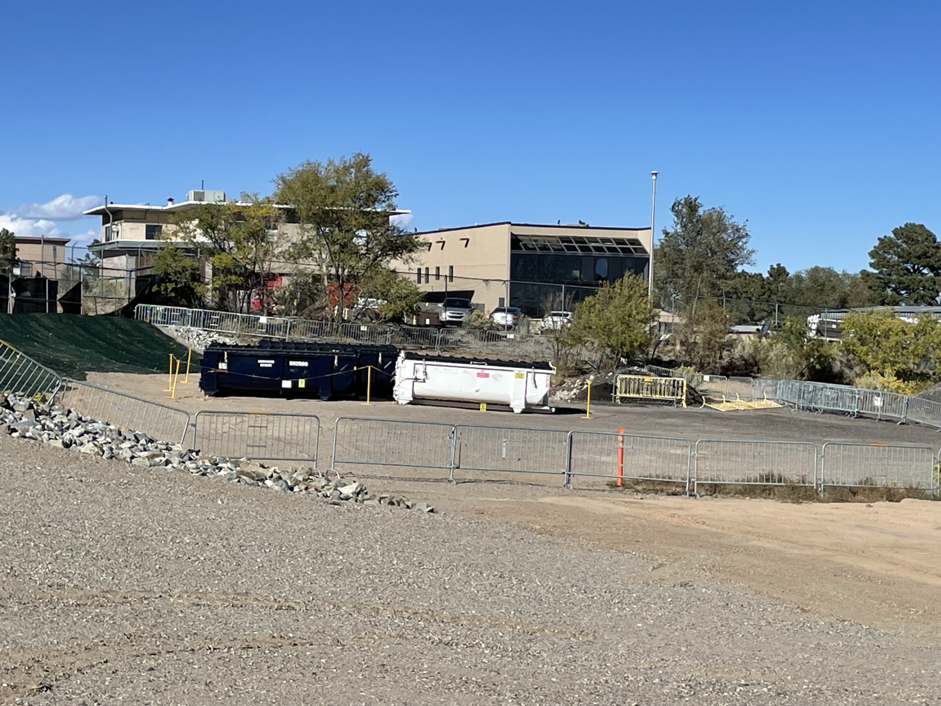 2 large dumpsters in the middle of a work field site