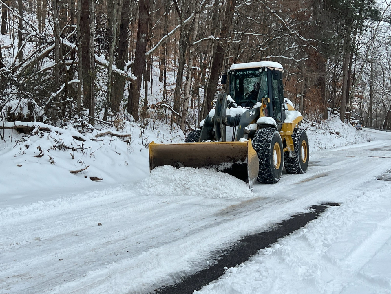 A bulldozer clears snow off a road