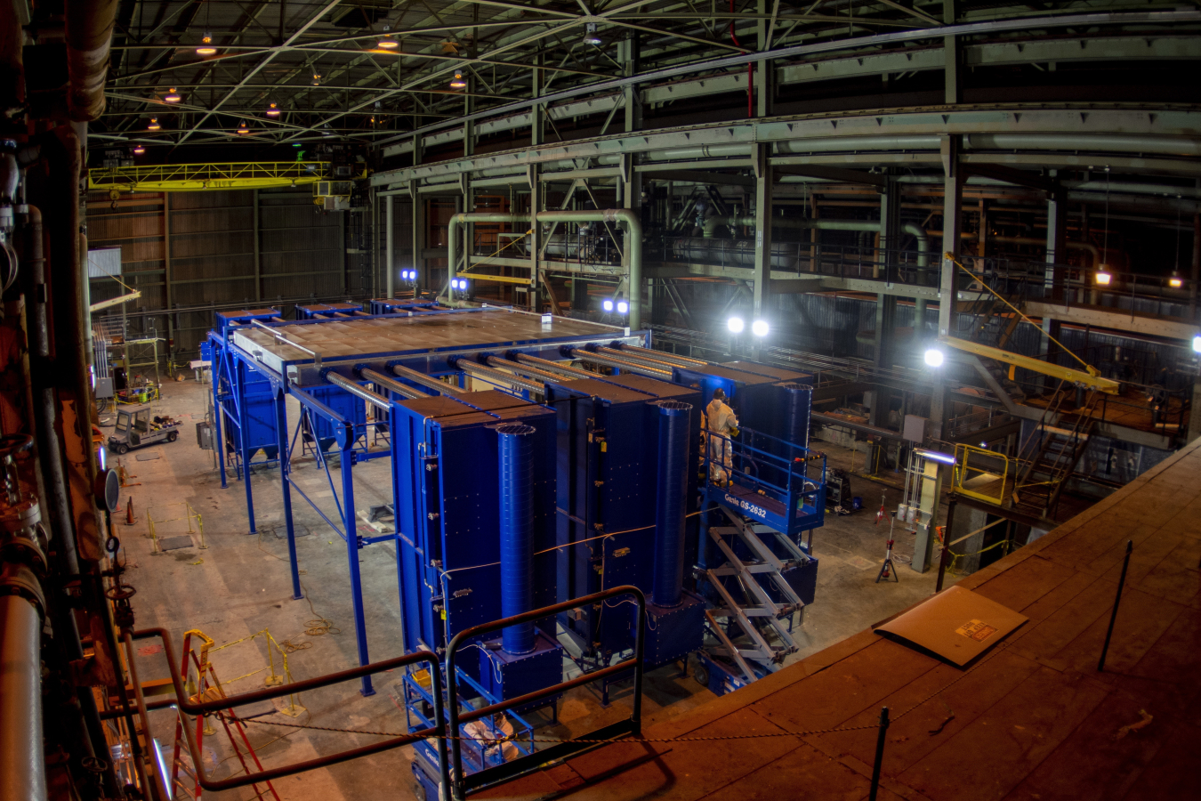 The inside of a dark industrial building with a large blue ventilation machines