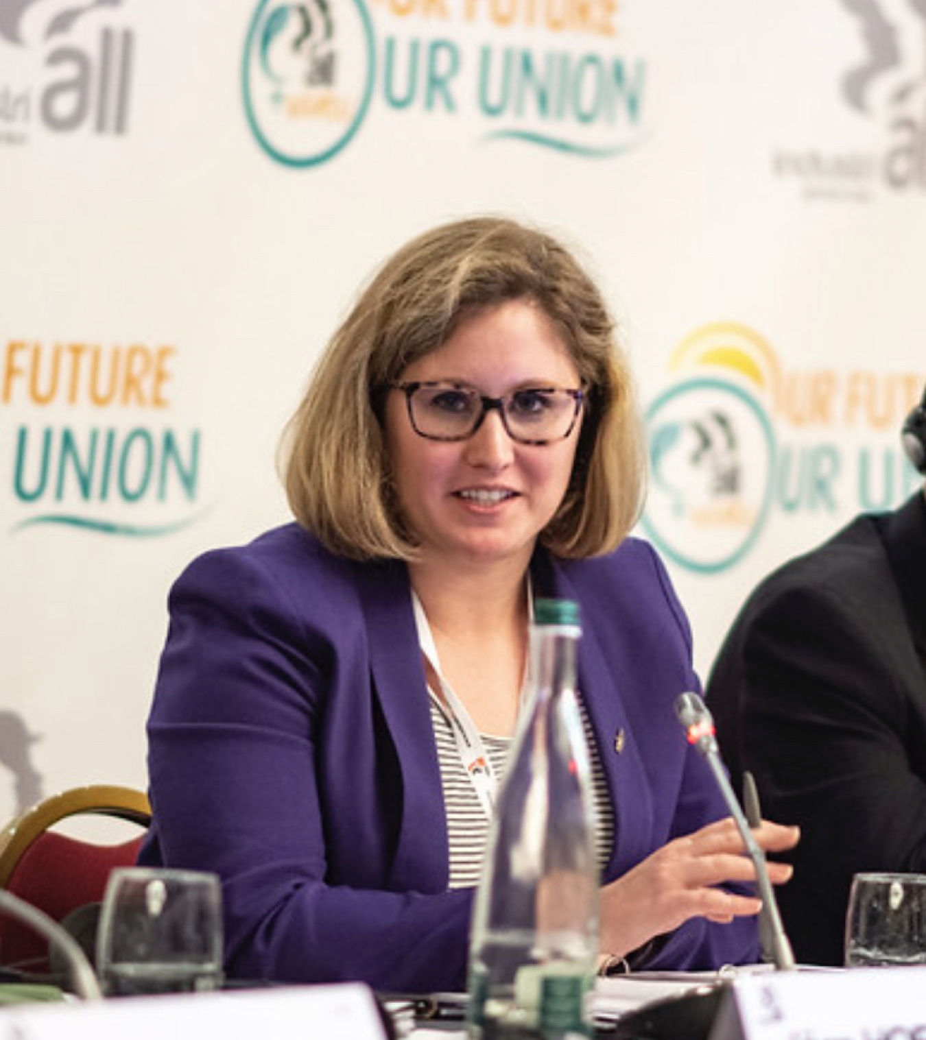 Anna Fendley sitting on a panel behind a microphone