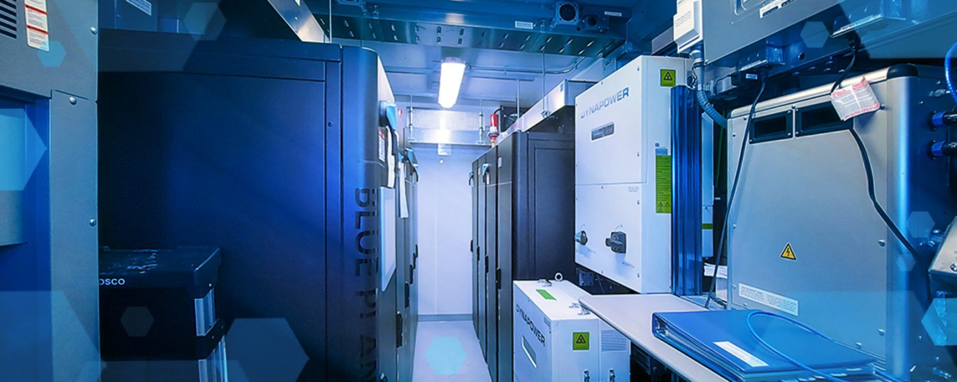 The inside of the Relocatable Resiliency Alternative Power Improvement Distribution Microgrid in a Box showing a couple of batteries as well as closed cabinets full of electronic equipment