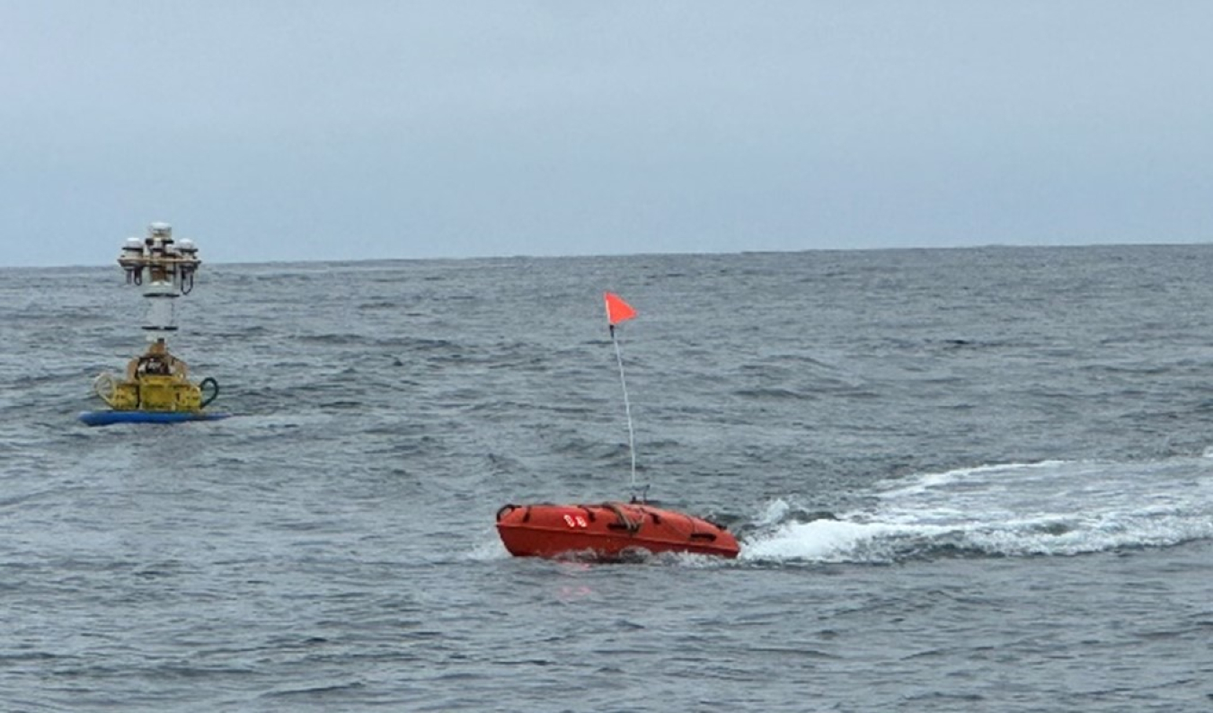 The SEARCHER device in the ocean with a spotter buoy in the background.