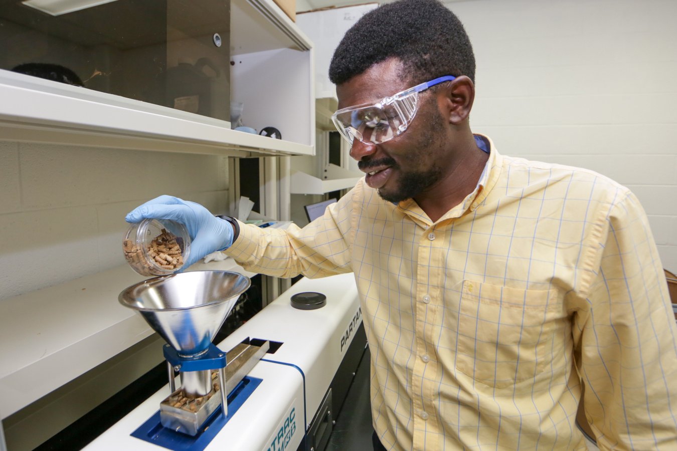 a photo of a person in a lab pouring a grain into a funnel