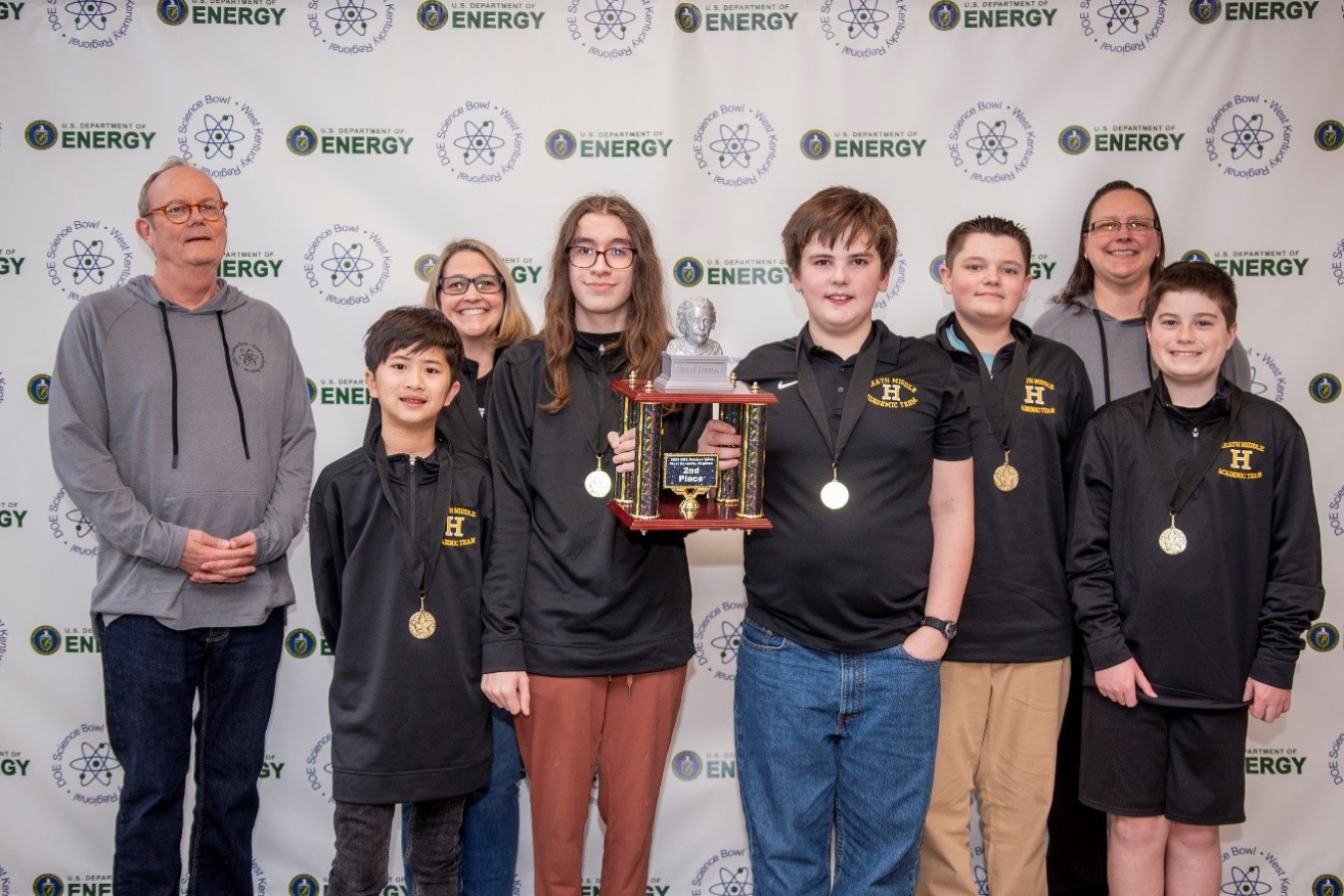 A group of middle school science bowl winner pose with a trophy