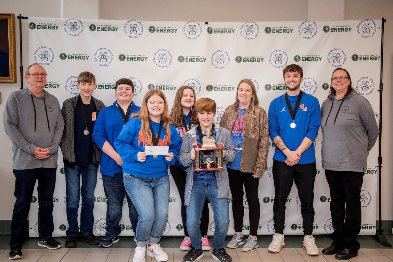 Group of middle school students pose for a picture with a trophy
