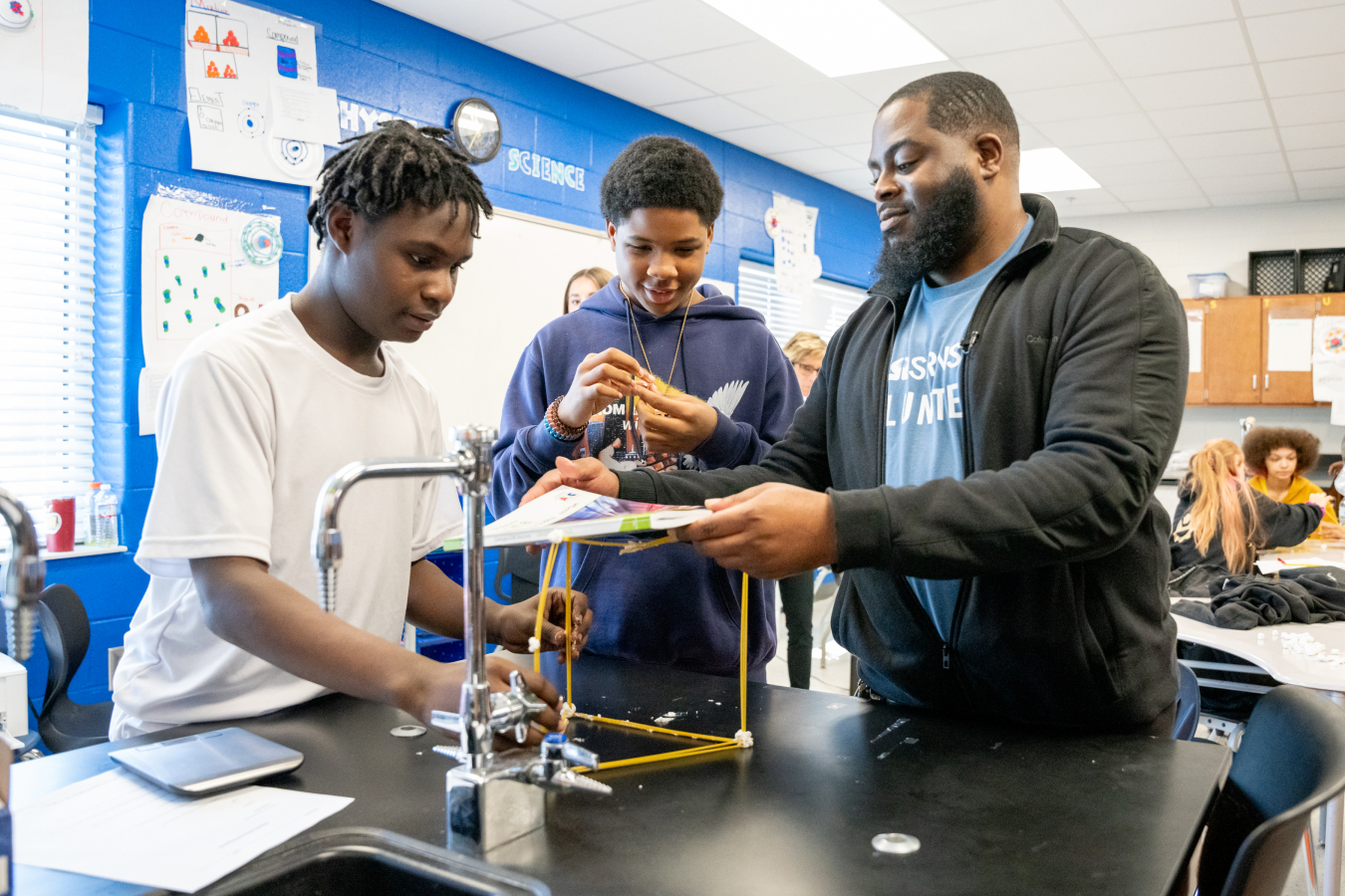 2 students and an engineer doing a science experiment 