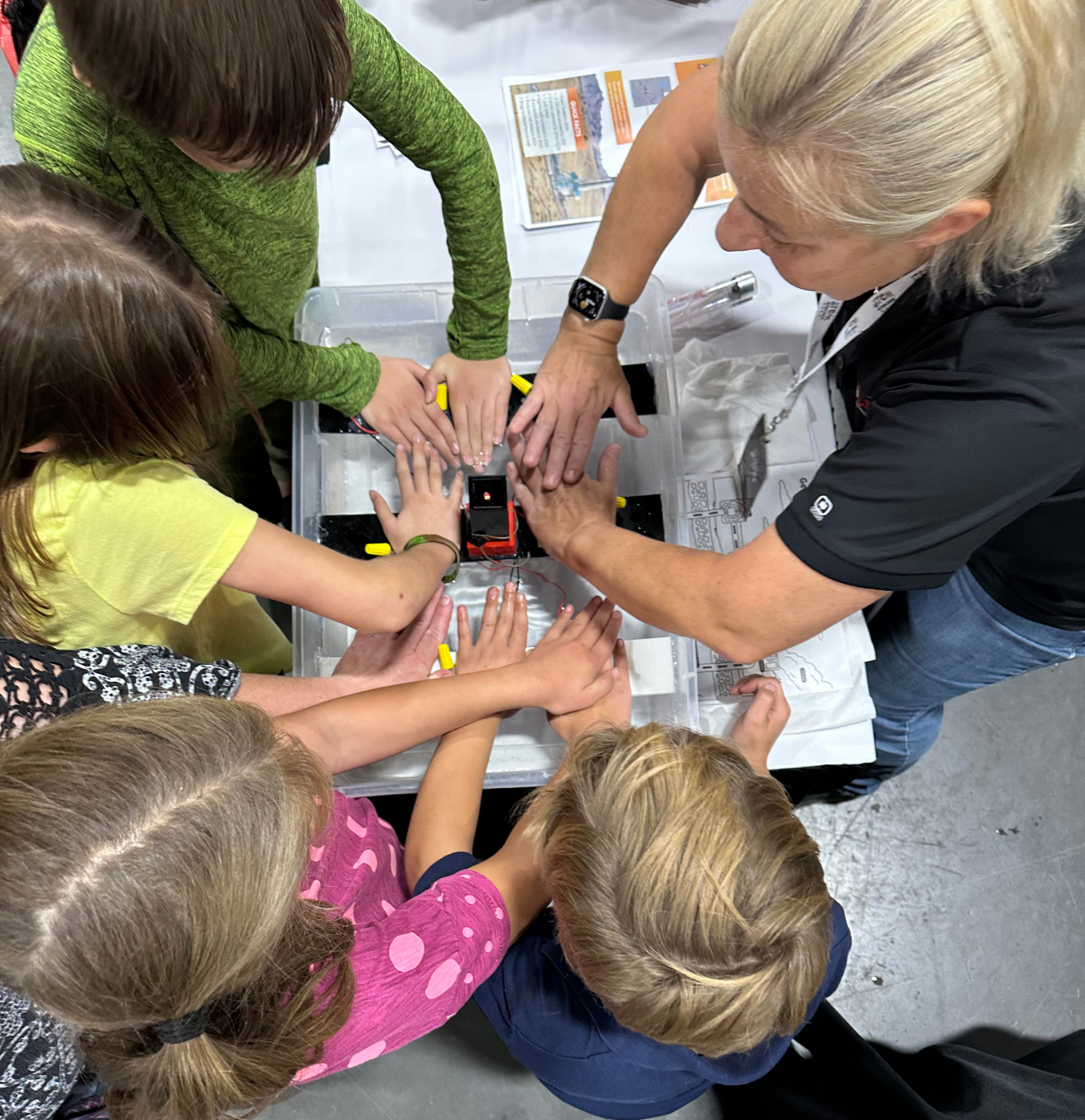 Utah FORGE's Gosia Skowron leads a small group of students in learning about heat transfer by placing their hands down flat on a Peltier Module.
