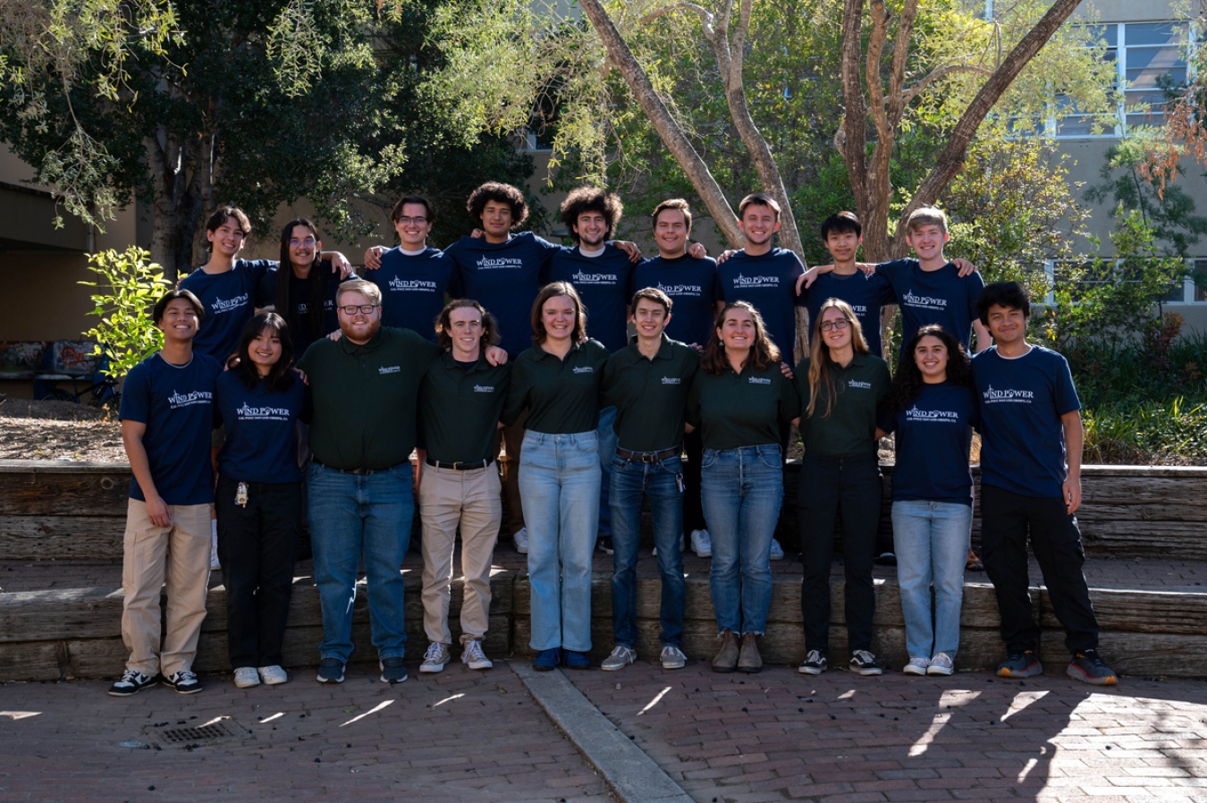 A group of people in matching shirts standing in front of some trees