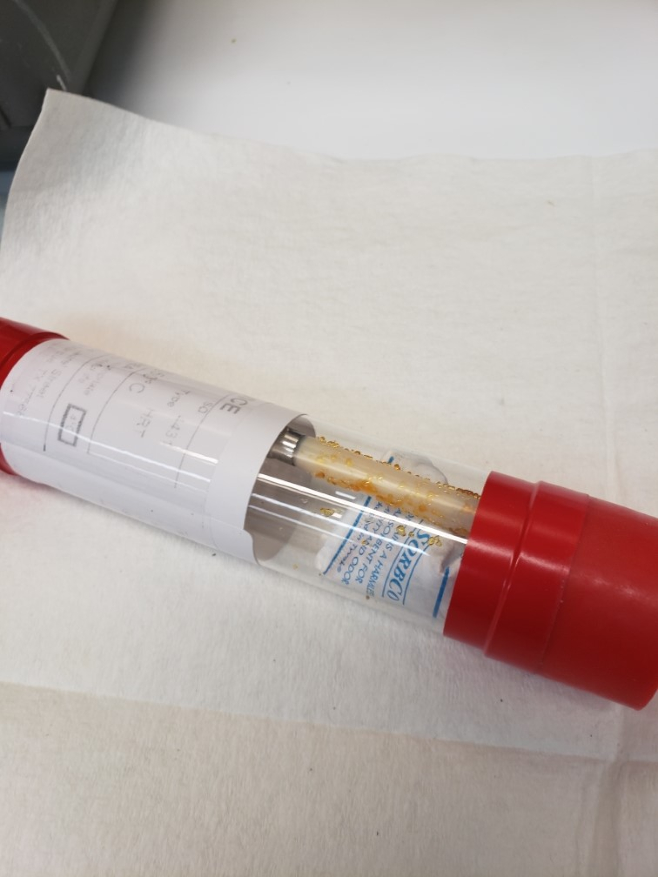 A clear vial with a crystal-like substance inside