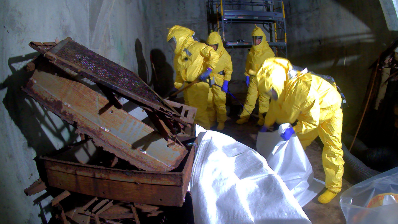 Team of workers in yellow hazmat suit working with metal materials and air filters