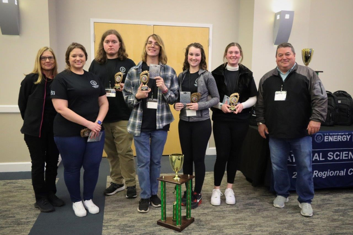 A group of high school students pose with a science bowl award winning trophy