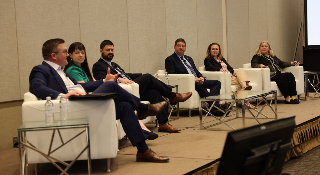 Panelists sitting in chairs on a stage speaking during a panel