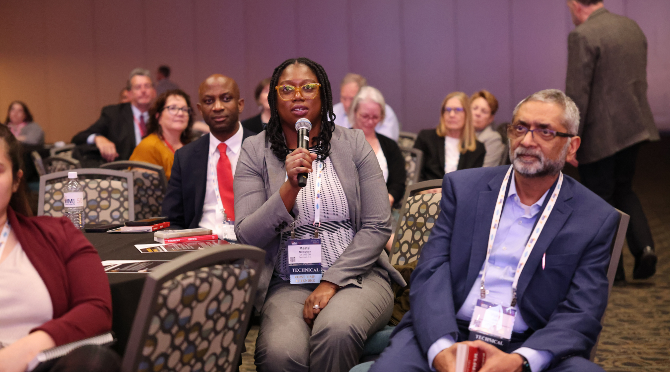 Audience member holding a microphone asking panelists a question