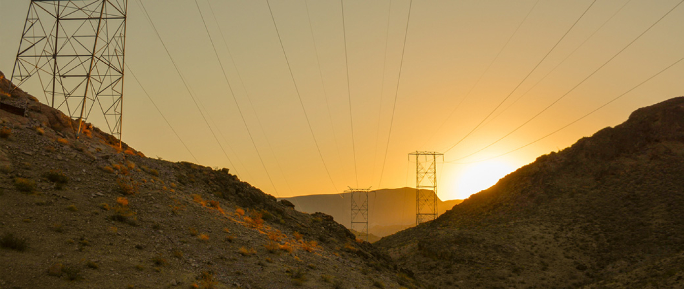 Photograph of a sunset over a canyon with transmission towers in the background