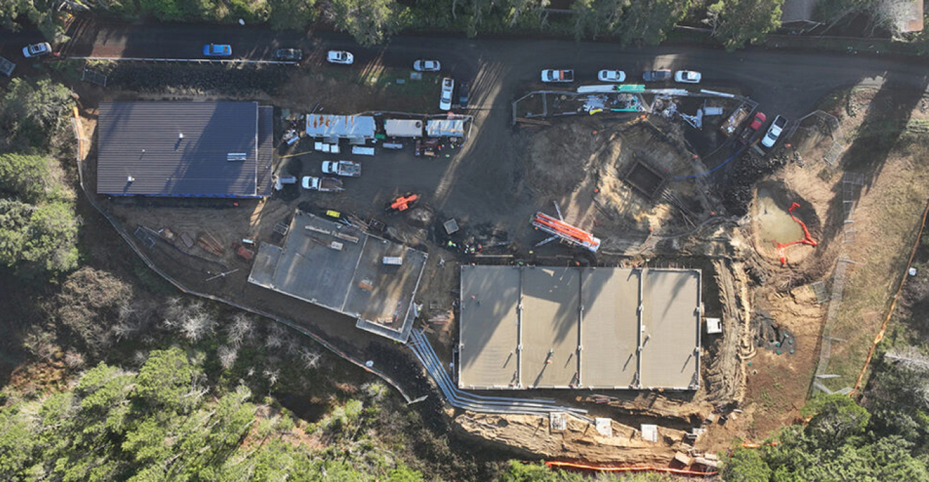 A bird's-eye view of the Utility Connection and Monitoring Facility while construction is ongoing. Many vehicles and some workers are visible. 