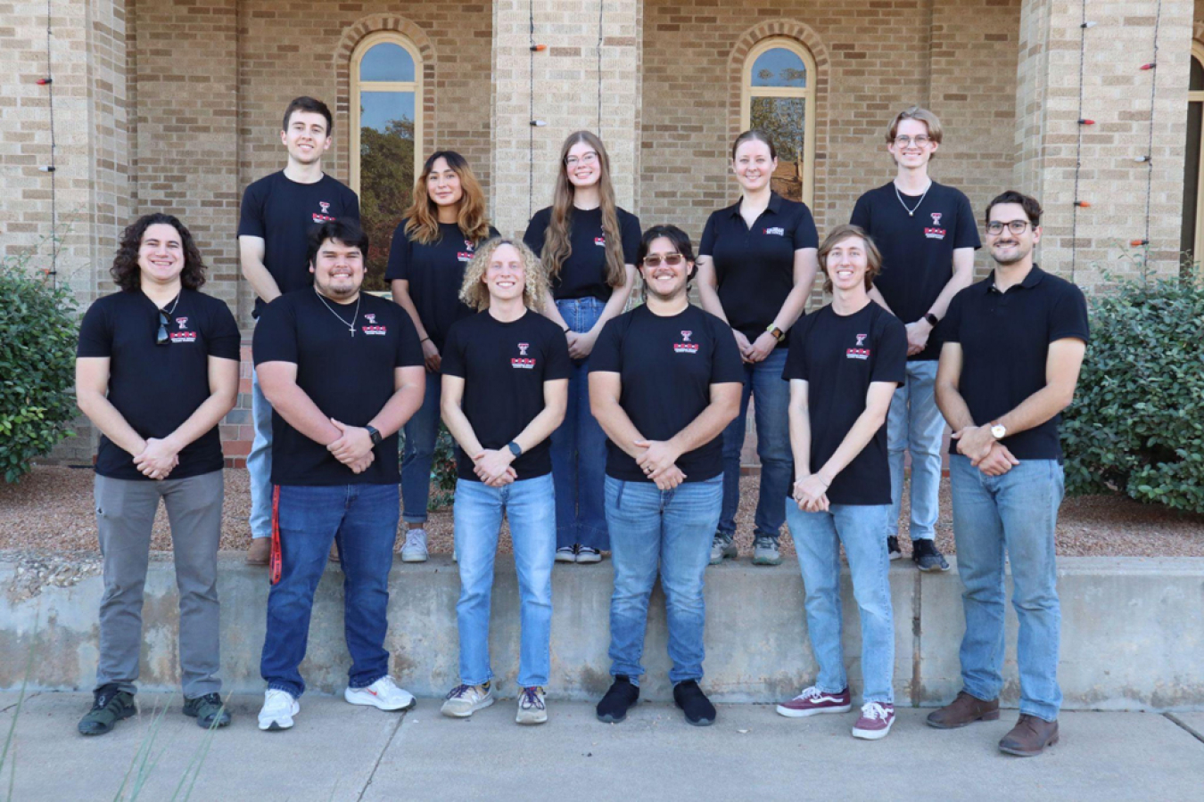 A group of people in matching shirts standing in front of a building. 