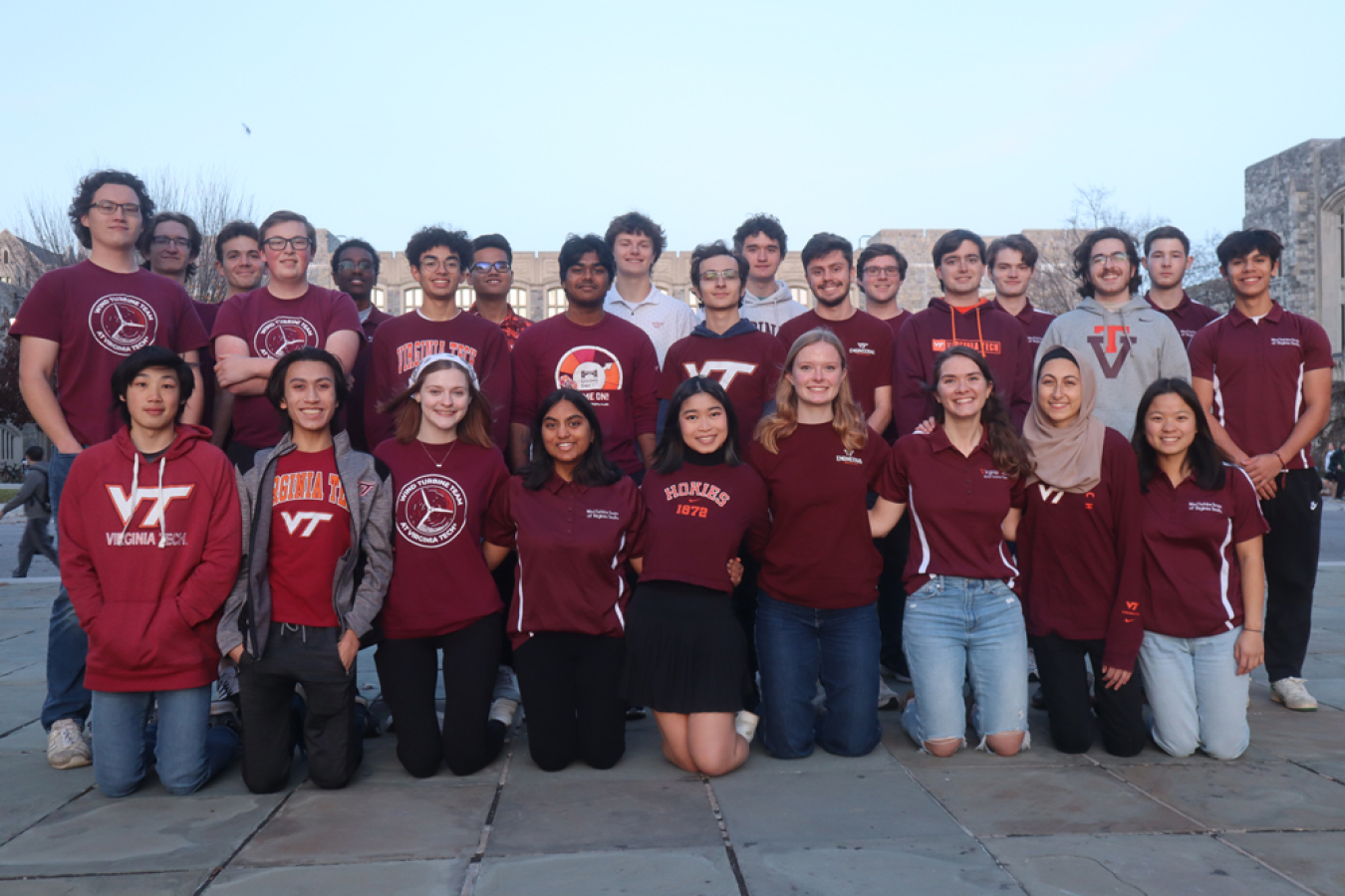 A group of people in Virginia Tech attire in front of a building.