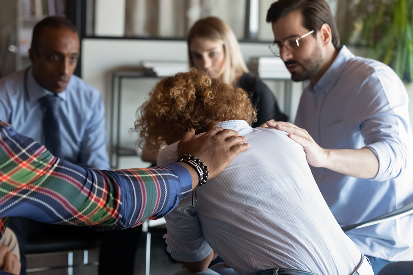 Supportive diverse people comfort upset woman at meeting