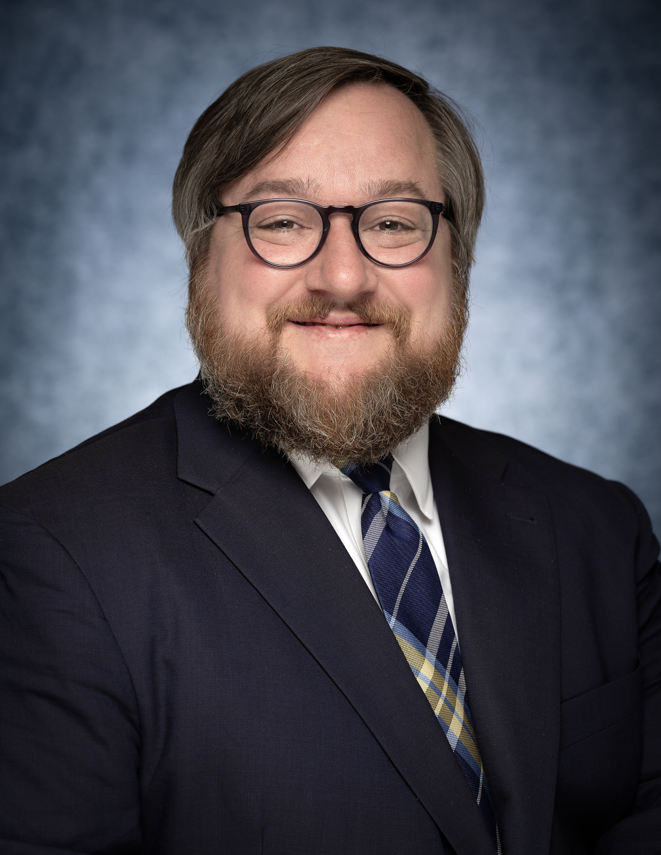 A man in a suit smiles at the camera. 